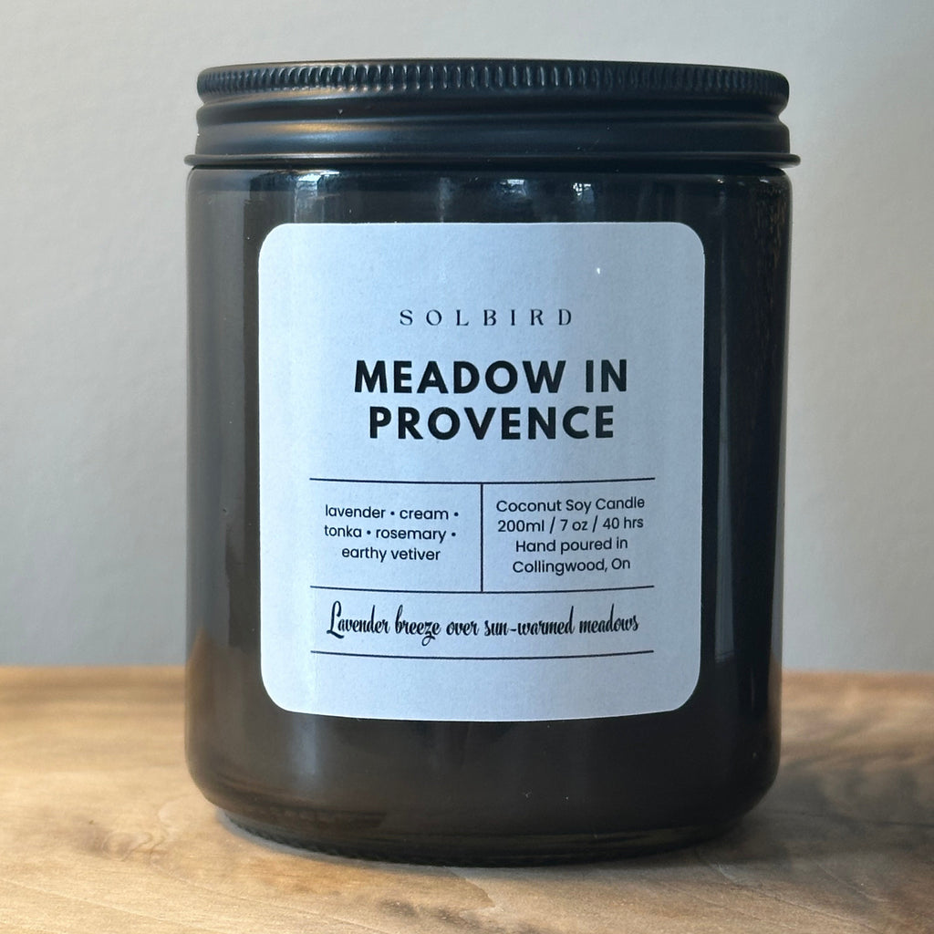 Black candle 
container with a label on a wooden surface